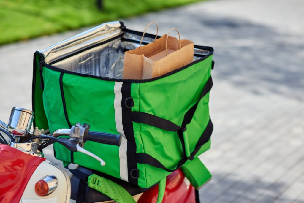 Green delivery thermo backpack with food on scooter. Delivery services